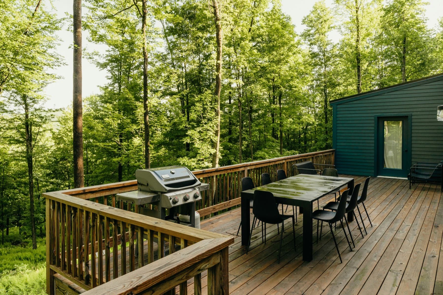 Finished wood deck with railing, outdoor dining area, and wooded view