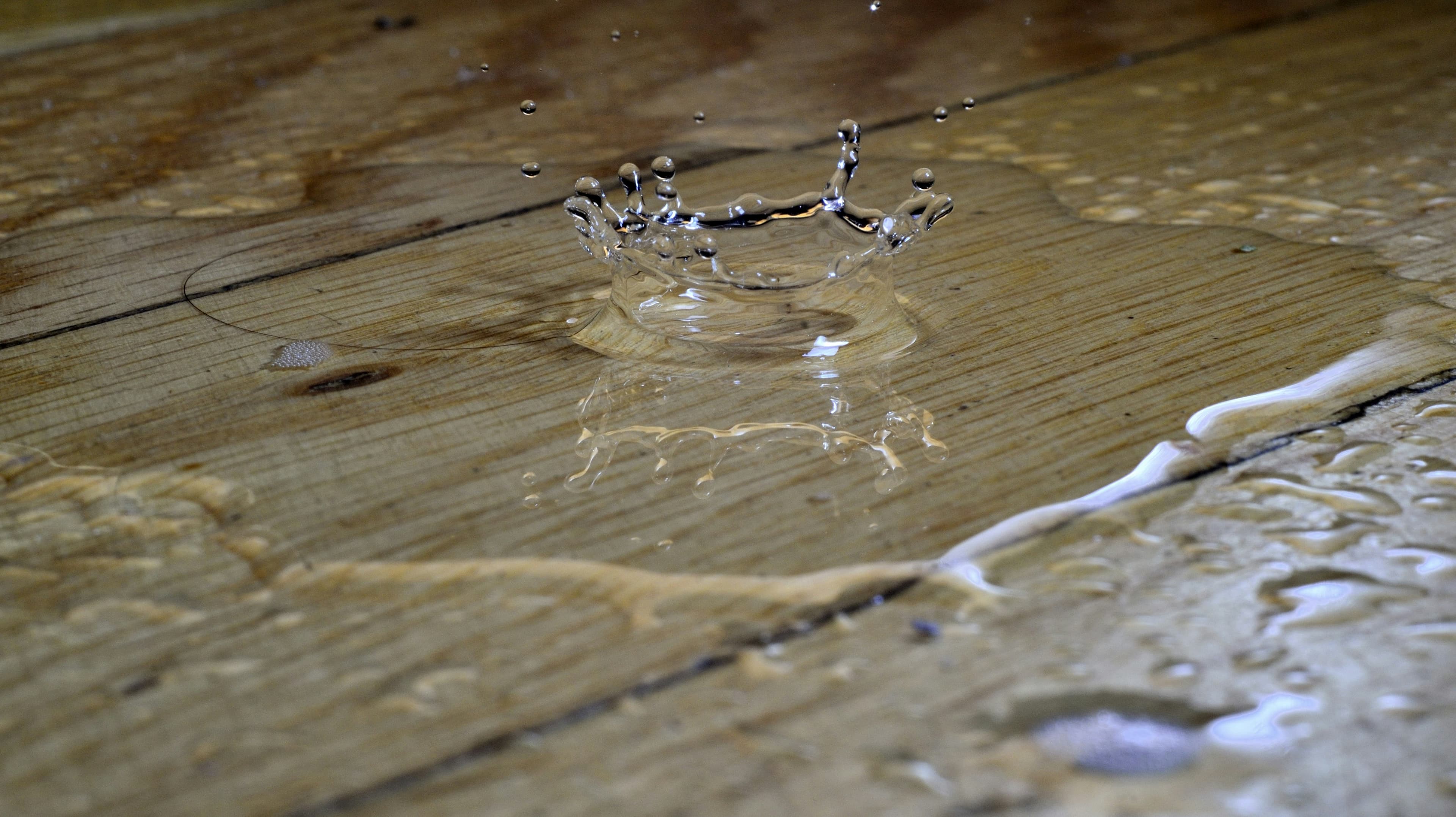 Water droplet splashing onto a wet wood floor