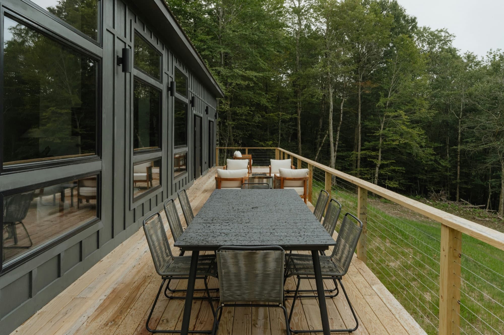 Wood deck with cable railing, outdoor dining furniture, and a wooded view
