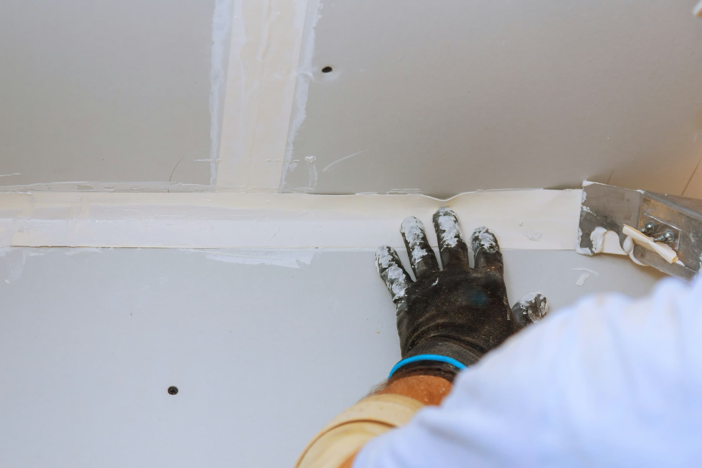 Drywall finisher smoothing joint compound over a taped seam