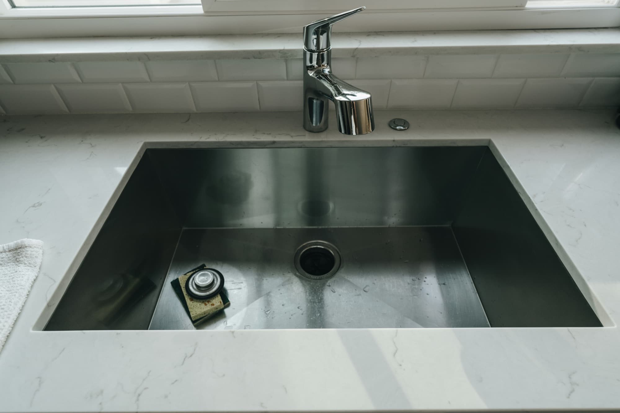 Stainless steel undermount kitchen sink with a chrome faucet and marble-look countertop