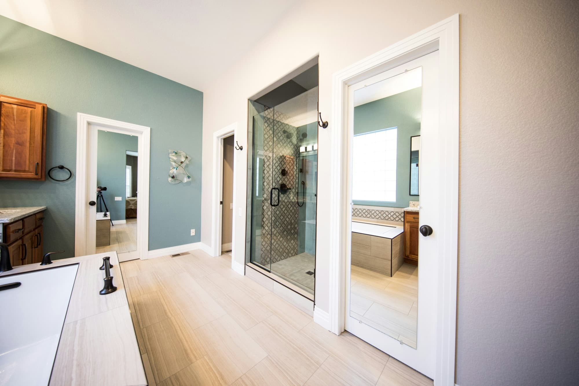 Finished primary bathroom with a glass shower, tiled floor, mirrors, and white trim