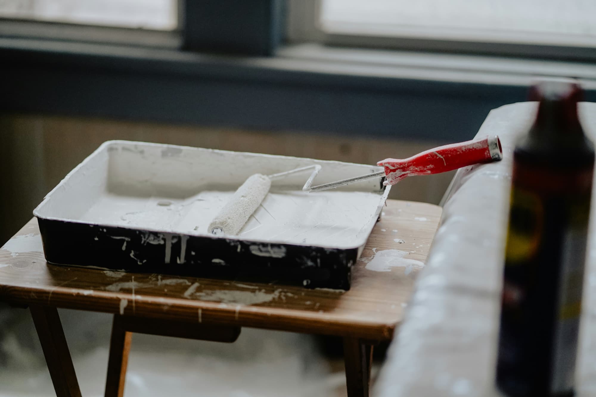 Paint roller resting in a tray during an interior painting project