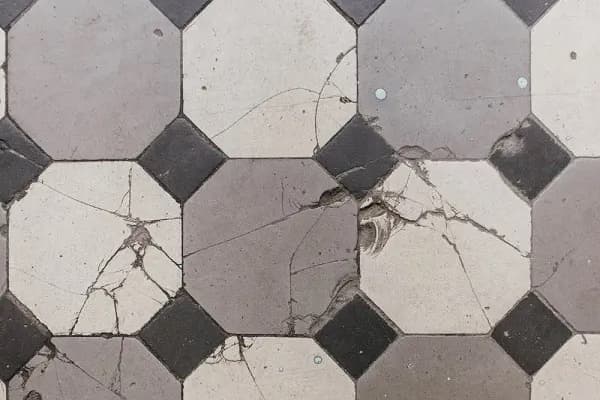 Several cracked floor tiles in a gray geometric pattern