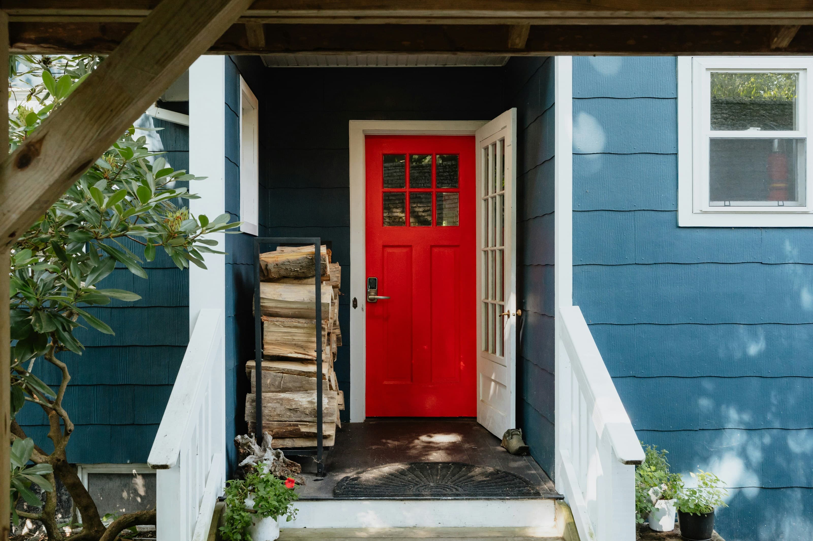 Red front door standing open on a blue house