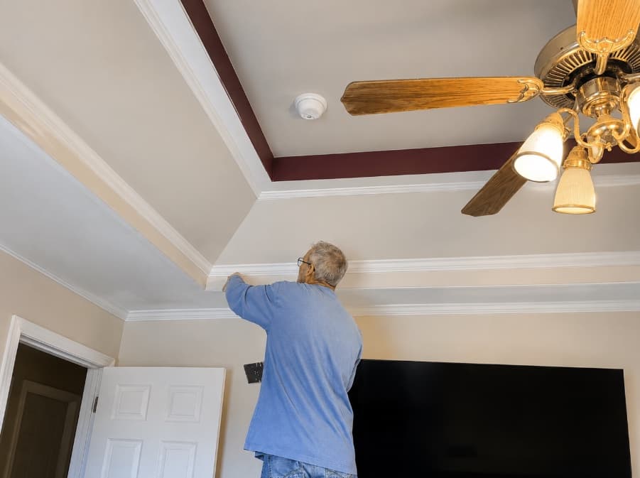 Ken completing finish work above a wall-mounted television
