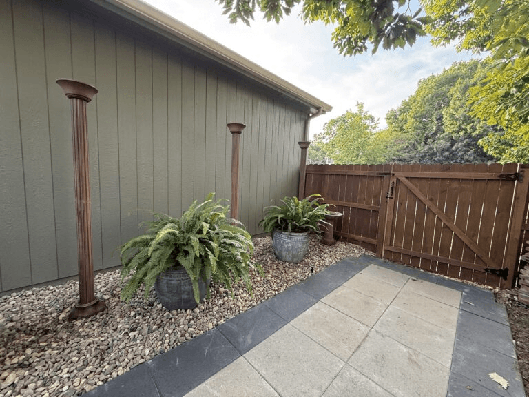 Outdoor planters and tall landscape lights installed along a backyard patio
