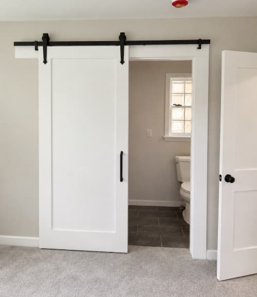 White sliding barn door installed on black hardware