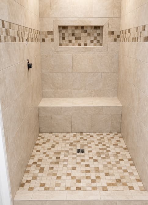 Tan tile shower with a full-width bench and recessed niche