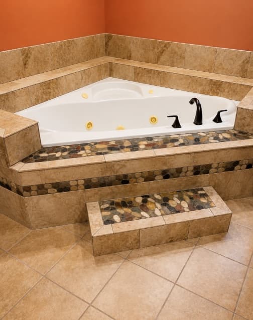 Built-in soaking tub with stone tile and pebble accents